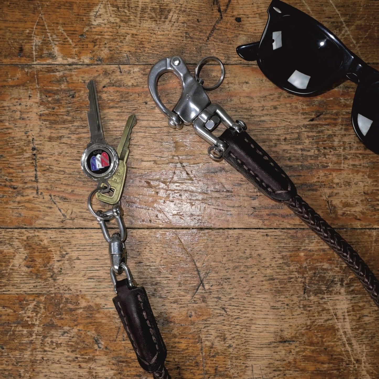 Leder Schlüsselkette im Wallet Chain Style mit Edelstahl-Karabiner, Schlüsselring und geflochtenem Echtleder auf Holzuntergrund.